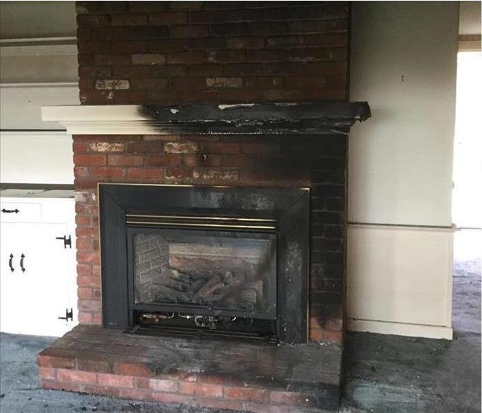 bharred fire place and mantle, white bookcases dirty with soot