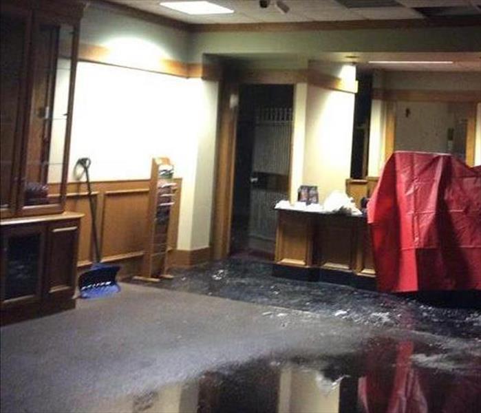 soaked and flooded carpet in a bank, red tarp covering counter area