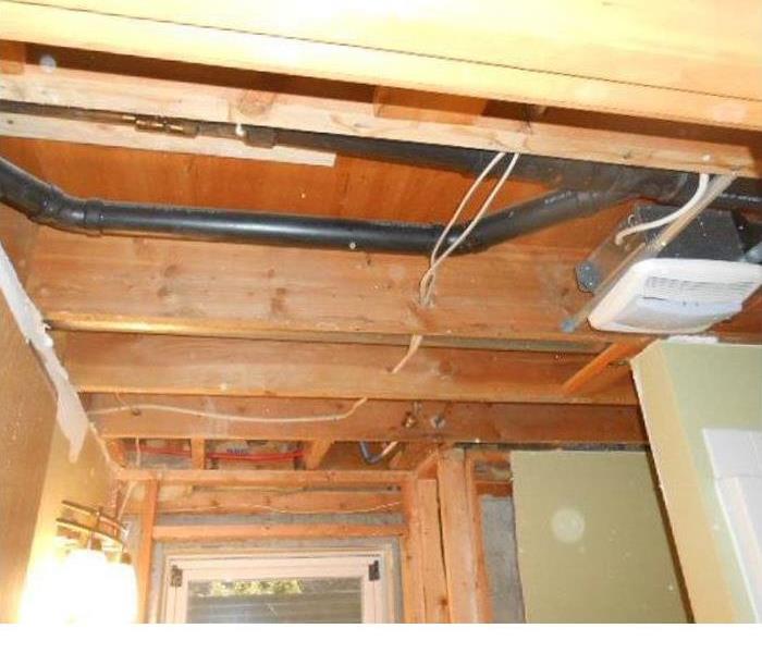 opened ceiling, showing black drain line and structural wood