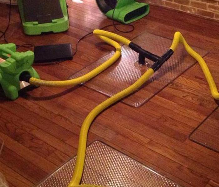 THREE DRYING MATS, HOOKED UP WITH YELLOW HOSES ON A HARDWOOD FLOOR