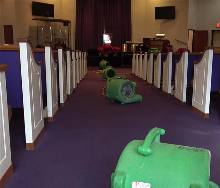 four air movers drying out aisle in a church, purple carpet